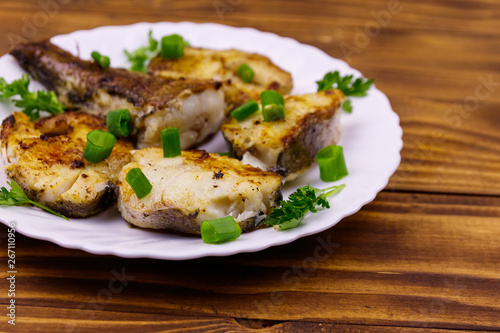 Roasted pollock in white plate on a wooden table