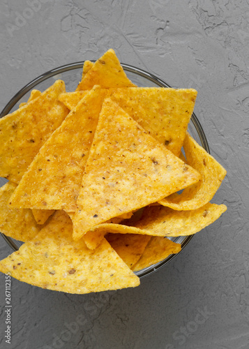 Full bowl of tortilla chips on concrete background, top view. Mexican food. From above, overhead, flat lay.