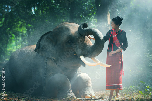 Beautiful young Thai woman northeast style is enjoy dancing and playing with elephant in the jungle in Surin, Thailand.