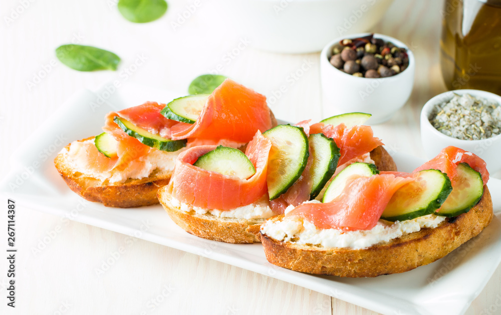 Salmon, cucumber and cream cheese bruschetta. Italian tapas, antipasti with vegetables, herbs and oil on grilled ciabatta and baguette bread. Sandwich. Salmon, cucumber and cream cheese bruschetta. Italian tapas, antipasti with vegetables, herbs and oil on grilled ciabatta and baguette bread. Sandwich.
