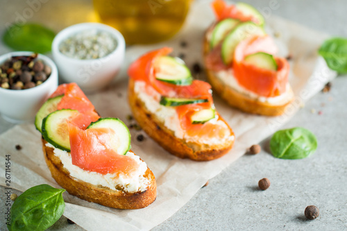 Salmon, cucumber and cream cheese bruschetta. Italian tapas, antipasti with vegetables, herbs and oil on grilled ciabatta and baguette bread. Sandwich.