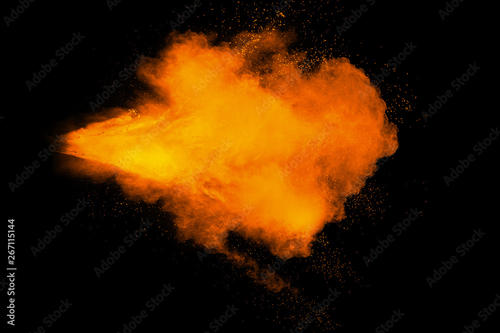 Abstract yellow orange powder explosion on black background. Freeze motion of yellow orange dust particles splash.