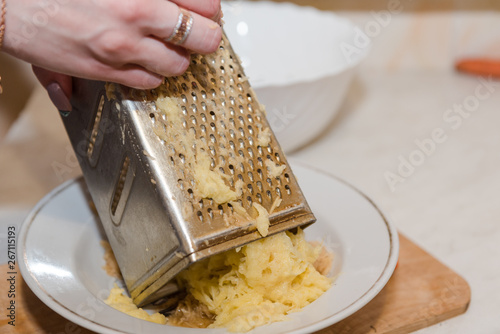 Grate the potatoes. A woman is rubbing grated potatoes. Natural food.