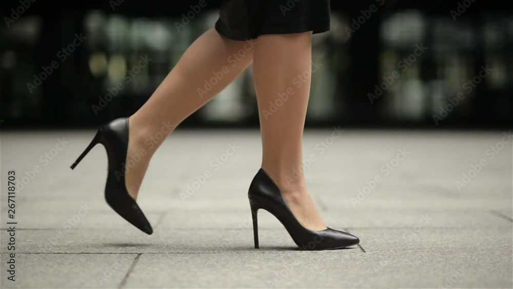 Female Legs In High Heels Shoes Walking In The Urban Street. Feet Of Young Business Woman In High-Heeled Footwear Going In The City. Girl Stepping To Work. Slow Motion Close Up. Female Legs In High Heels Shoes Walking In The Urban Street. Feet Of Young Business Woman In High-Heeled Footwear Going In The City. Girl Stepping To Work. Slow Motion Close Up.