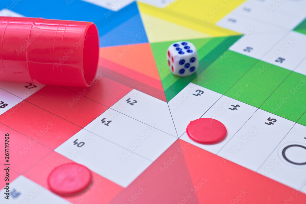 Red beaker, a dice and a red pawn on a parchisi board Stock Photo | Adobe  Stock