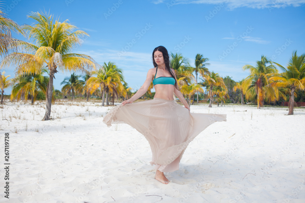 girl travels to sea and is happy. Young attractive brunette woman dancing waving her skirt against tropical landscape