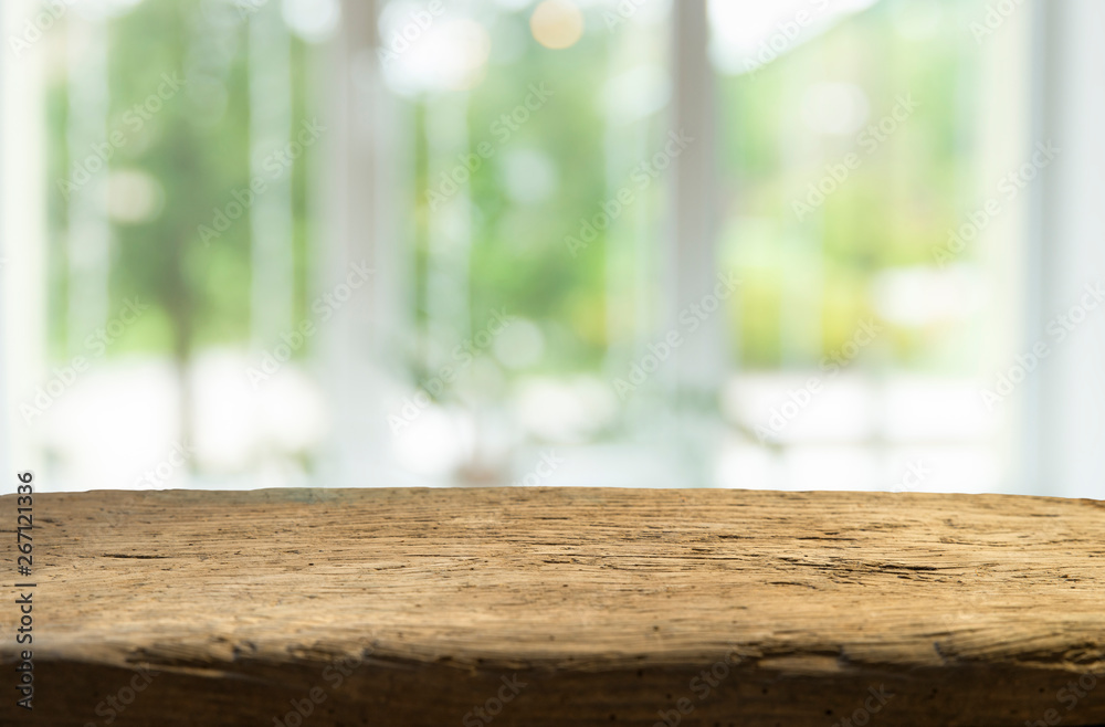 Wood table top on blur of window glass and abstract green from garden with city view in the morning background. For montage product display