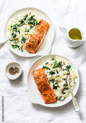 Healthy balanced lunch - creamy spinach orzotto and baked salmon on a light background, top view