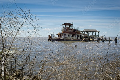 Tablou pe pânză A rusted out abandon tug boat in the water just off the shore of Lake Pontchartr