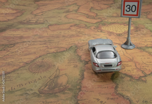 Travel concept. Toy car on vintage World map with road sign.