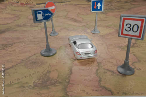 Travel concept. Toy car on vintage World map with road sign.