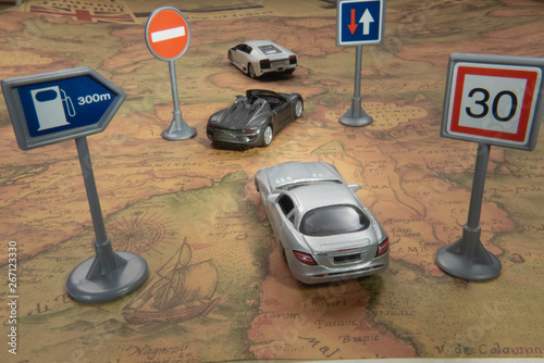 Travel concept. Toy car on vintage World map with road sign.