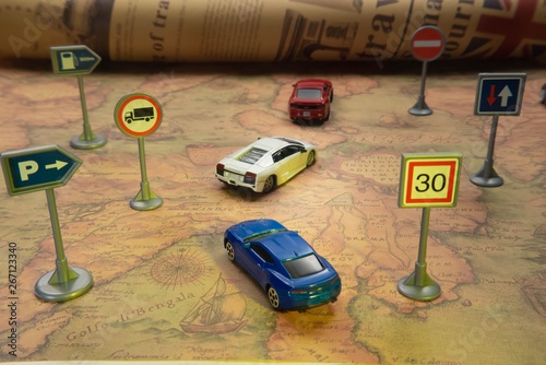 Travel concept. Toy car on vintage World map with road sign.