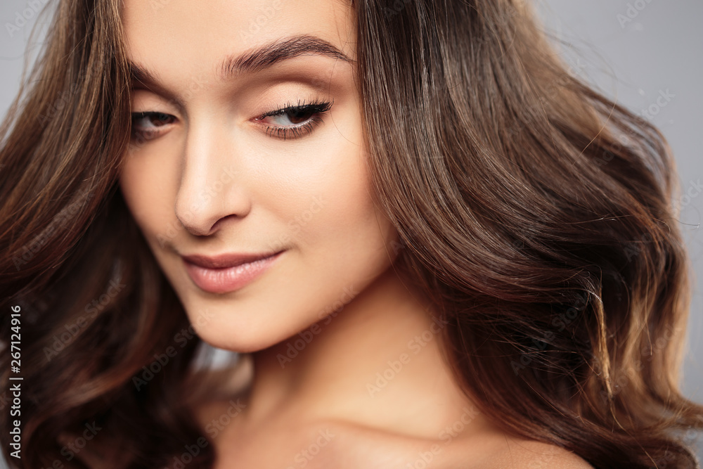 Brunette girl with healthy curly hair and natural make up . Beautiful model woman with wavy hairstyle .Care and beauty Brunette girl with healthy curly hair and natural make up . Beautiful model woman with wavy hairstyle .Care and beauty