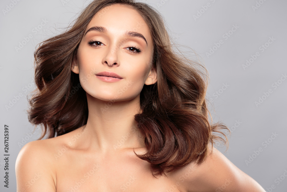 Brunette girl with healthy curly hair and natural make up . Beautiful model woman with wavy hairstyle .Care and beauty Brunette girl with healthy curly hair and natural make up . Beautiful model woman with wavy hairstyle .Care and beauty