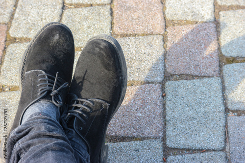 A man shoes resting on stone paving floor ground.