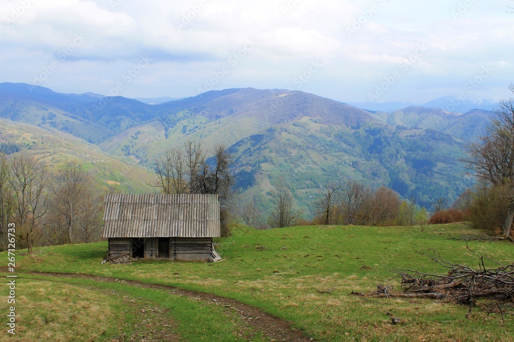 An abandoned wooden house on a hill on the background of mountains