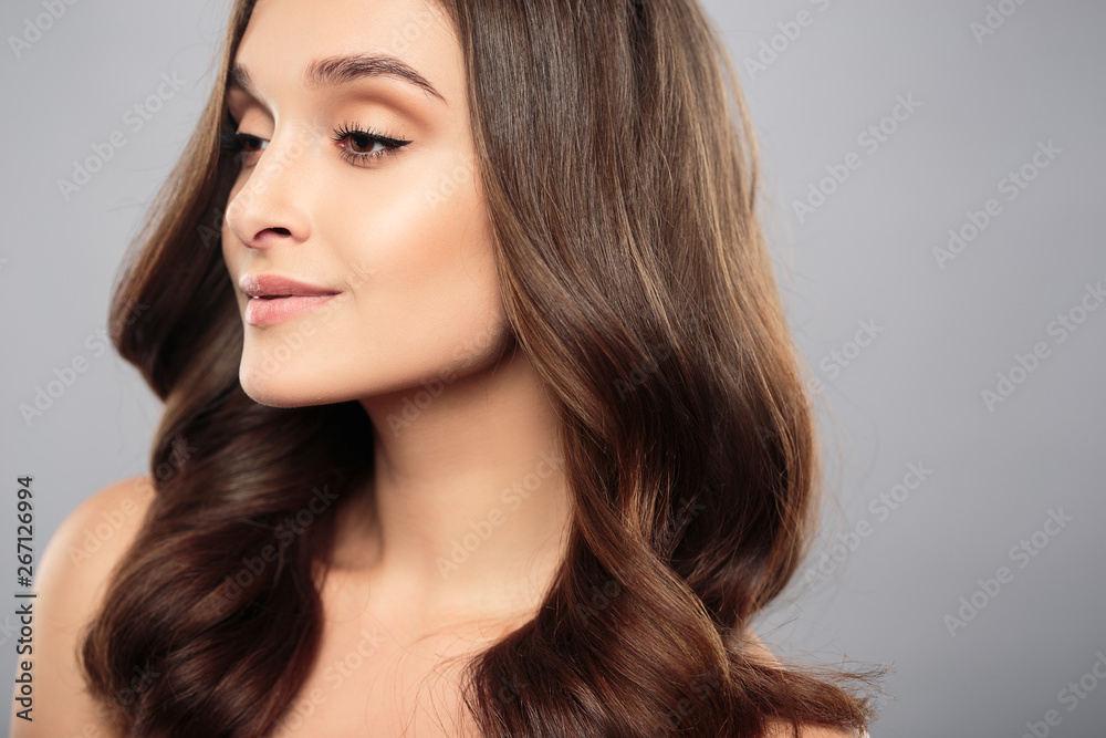 Naklejka premium Brunette girl with healthy curly hair and natural make up . Beautiful model woman with wavy hairstyle .Care and beauty
