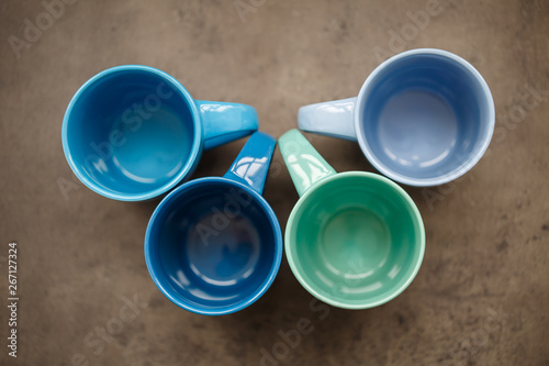 four tea mugs of different colors on a gray background