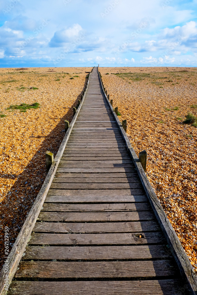 long straight wooden pathway on pebble beach long straight wooden pathway on pebble beach