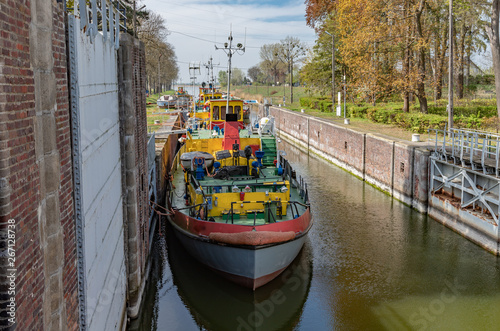 Obraz na płótnie Sluice, water gate with colorful tugboats parked along the berth in Sobieszewo in Poland. w salonie