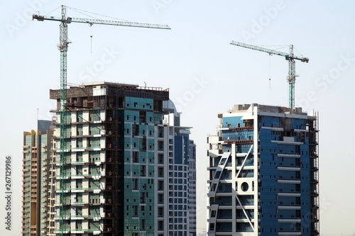 Picture of buildings under constructions with cranes on top of the structures. Construction work site background.