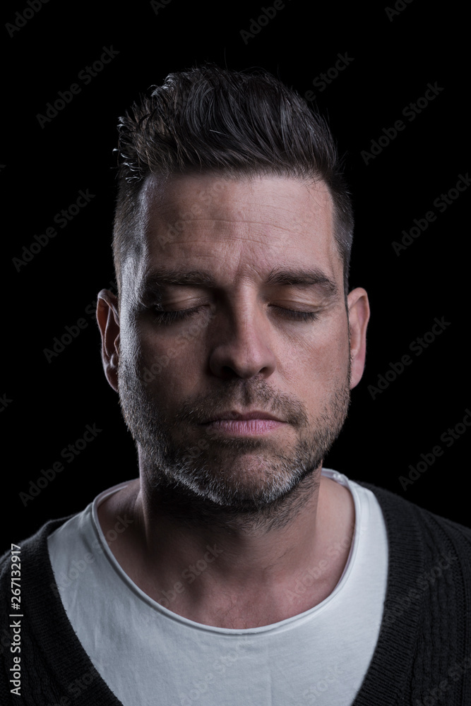 Studio portrait of a serious man with closed eyes. Isolated on black background. Vertical. Closeup. Studio portrait of a serious man with closed eyes. Isolated on black background. Vertical. Closeup.