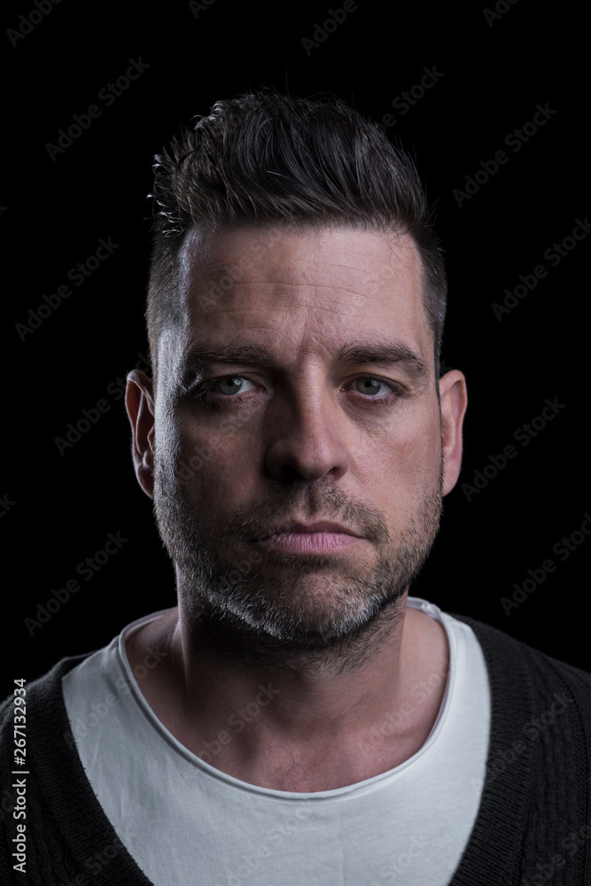Studio portrait of a caucasian serious man looking at the camera. Isolated on black background. Vertical. Closeup. Studio portrait of a caucasian serious man looking at the camera. Isolated on black background. Vertical. Closeup.