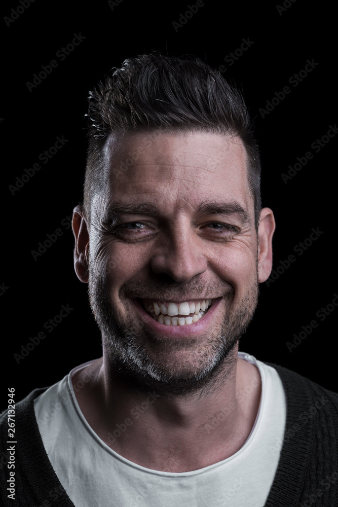 Studio portrait of a smiling man looking at the camera. Isolated on black background. Vertical. Closeup. Studio portrait of a smiling man looking at the camera. Isolated on black background. Vertical. Closeup.