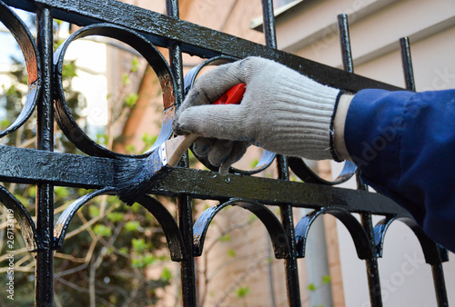 Worker paints a fence in black