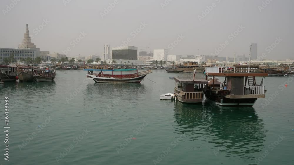 Old wooden dhow boat is slowly rocking in harbor of Doha Fishing boats Dhow in Doha Harbor in Doha, Qatar, Middle East Old wooden dhow boat is slowly rocking in harbor of Doha Fishing boats Dhow in Doha Harbor in Doha, Qatar, Middle East
