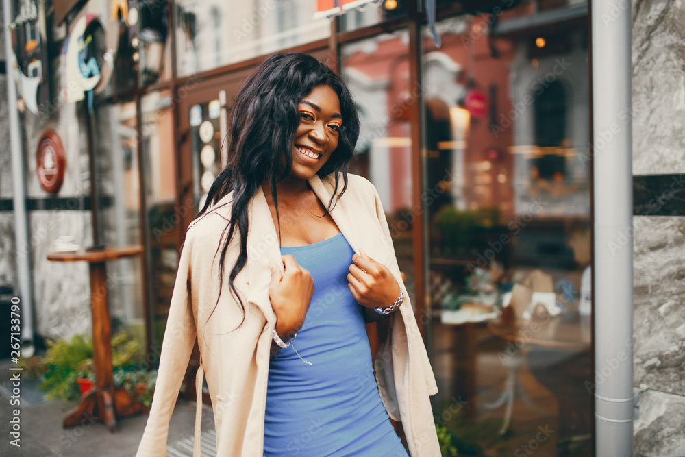 Elegant black woman standing in a autumn city. Businesswoman in a blue dress Elegant black woman standing in a autumn city. Businesswoman in a blue dress
