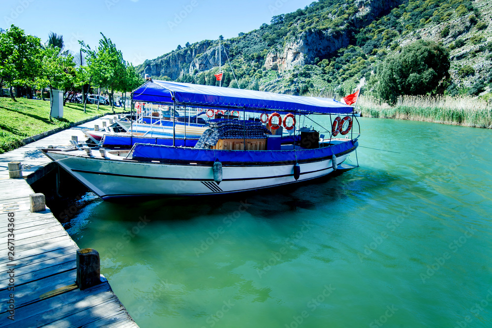 Tourist boat moored on the banks of the green river on the background of beautiful scenery Tourist boat moored on the banks of the green river on the background of beautiful scenery