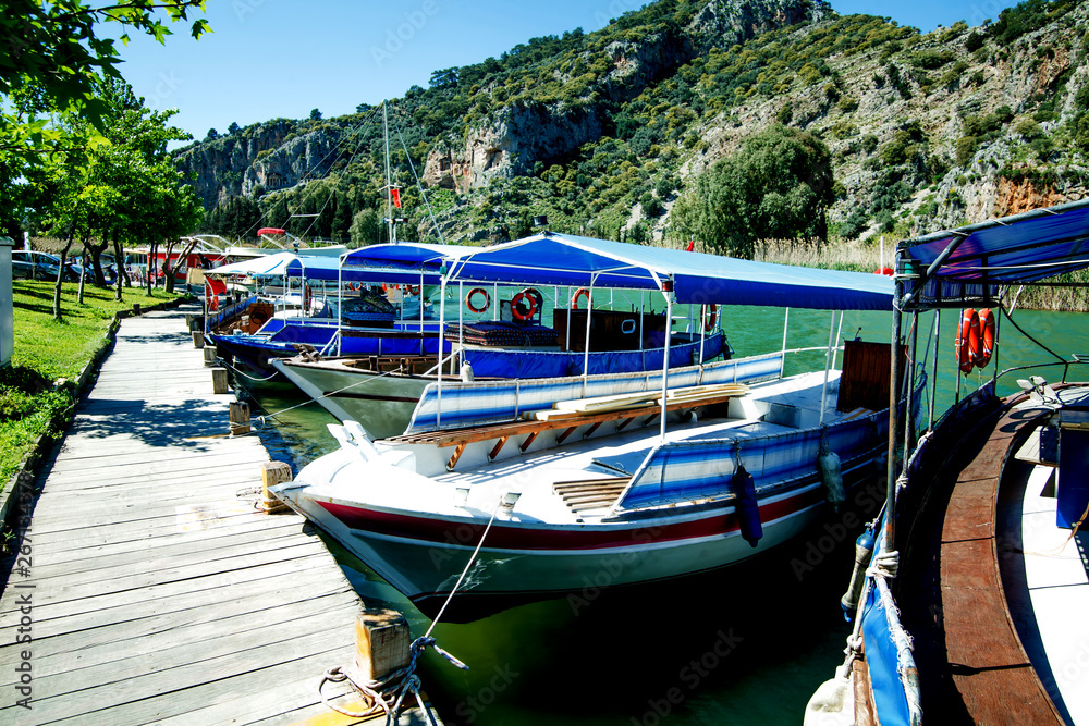Fototapeta premium Tourist boat moored on the banks of the green river on the background of beautiful scenery