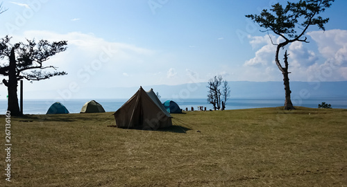 There are tents and trees on the lake shore. Lake Baikal. Summer landscape. Russia.