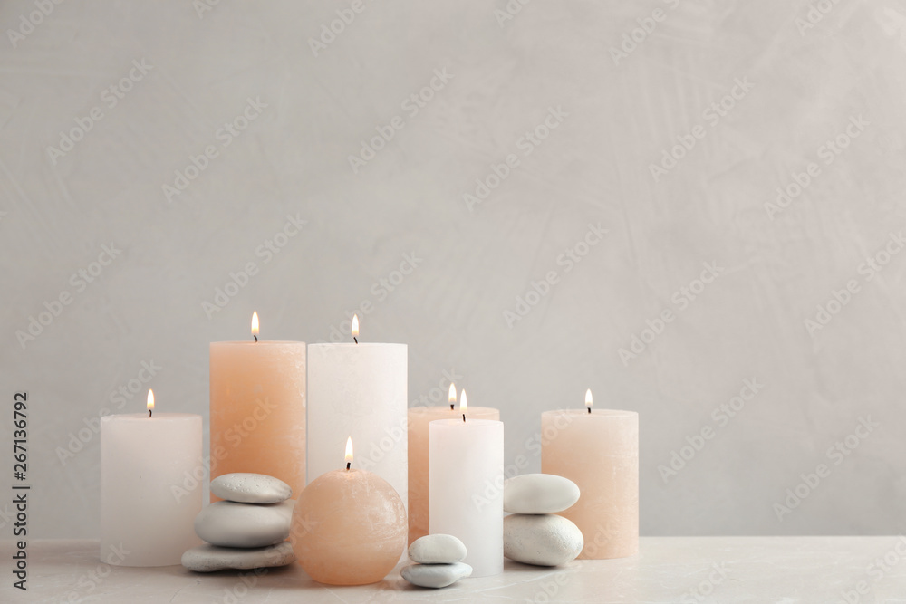 Beautiful composition with candles on table against grey background. Space for text