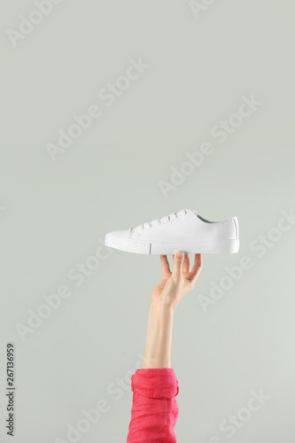 Woman holding sportive shoe on light background, closeup. Space for text