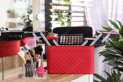 Beautician case with professional makeup products and tools on wooden dressing table photo