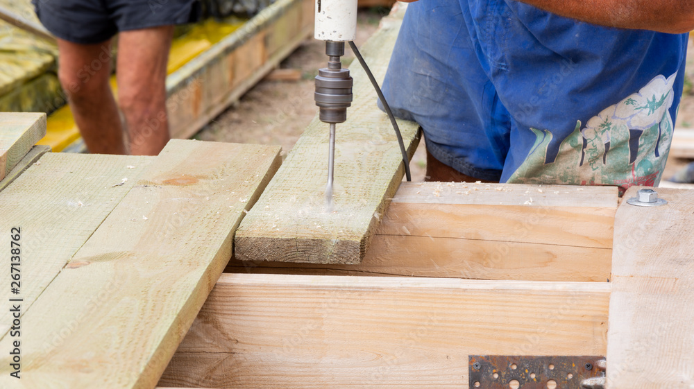 Handyman drills holes in the board at construction site Handyman drills holes in the board at construction site