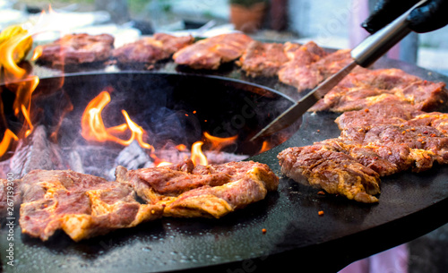 barbeque with fresh bloody steaks and open fire and the hand of a caterer