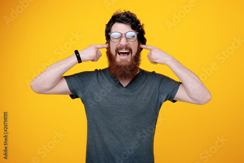 Canvastavla Photo of handsome man with closed eyes, scream and putting finger in his ears, s