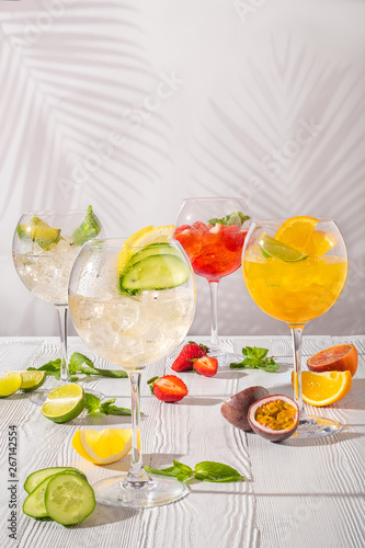 Assortment of cold lemonades in wine glasses on wooden table in morning sunlight