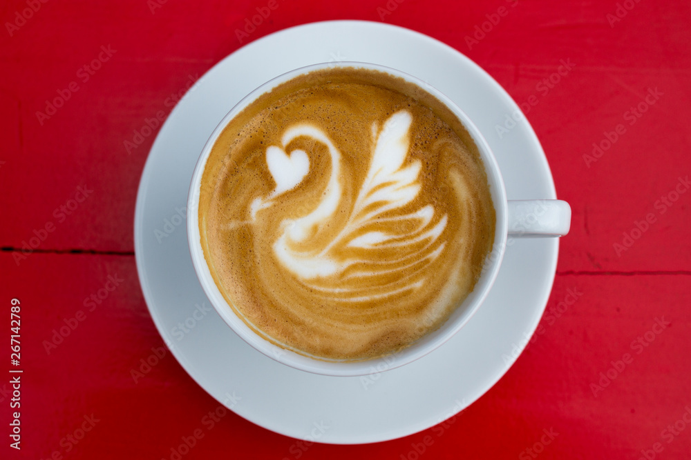 Cappuccino with stunning latte-art on a red background Cappuccino with stunning latte-art on a red background