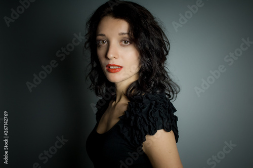 Studio portrait of sexy brunette woman with red sensual lips looking at the camera posing on black background