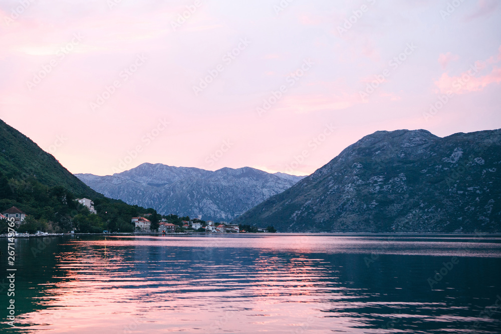 Beautiful view of the sunset or sunrise and the natural landscape with the sea and hills or mountains in Montenegro in the summer. Far coastal city.