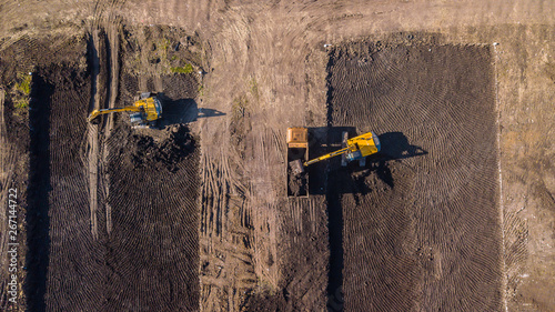 Aerial construction - top down view of an excavator and truck working on a construction site