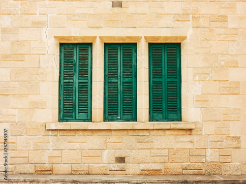 Green shutters on the old wall, made of stone