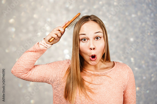 Portrait of a beautiful smiling young woman comb hair, on a background of gray sparkles