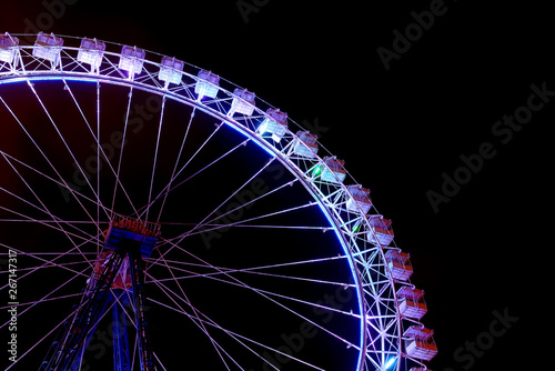 Part of ferris wheel with blue lighting at night.