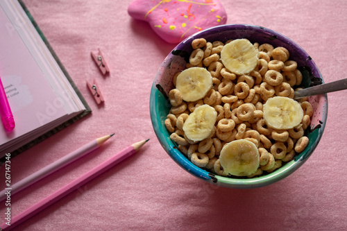 Cereal Cheerios Bowl with book and pencils over pink background 